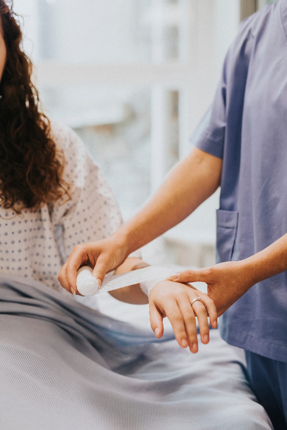 A clinician carefully wrapping a patient's hand with a fresh bandage.